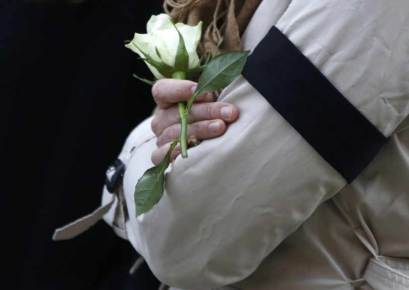 A woman holds a white rose as she observes a minute's silence in memory of the victims of the Paris shootings, at St George's Hall in Liverpool, Britain November 16, 2015. REUTERS/Phil Noble