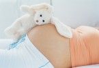 Stuffed rabbit on top of pregnant woman's belly --- Image by © Heide Benser/Corbis